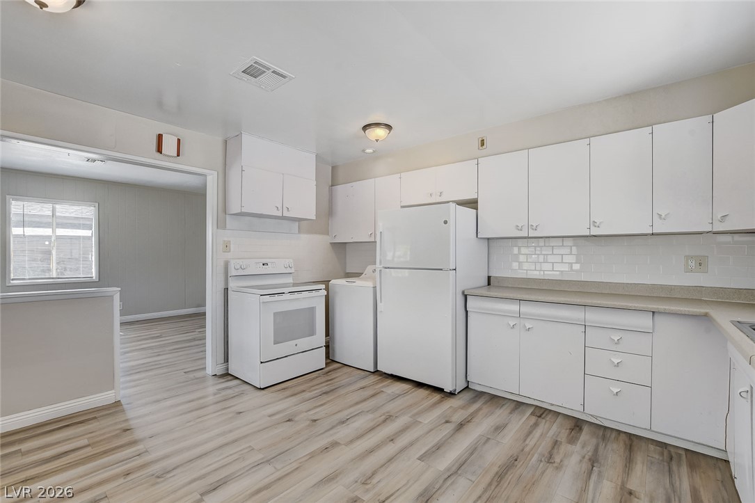 214 West Victory Road Henderson, NV 89015 - Photo 3 of 33 A well-lit kitchen with sleek white cabinetry and durable wood-look flooring awaits culinary adventures.