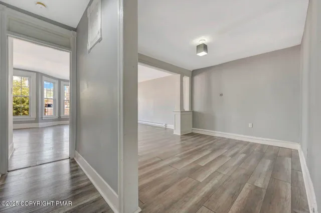 a view of an empty room with wooden floor and a window