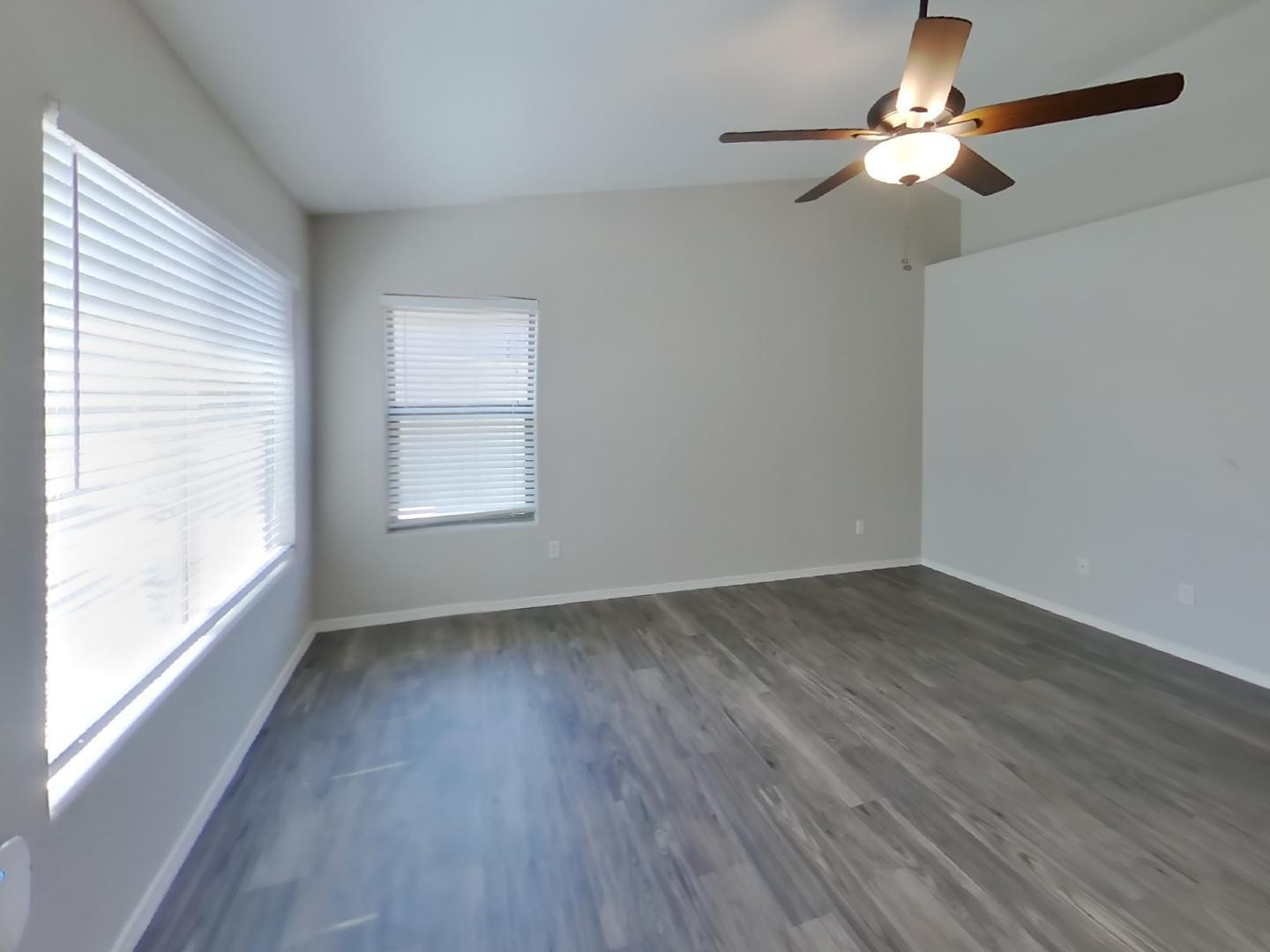 3194 West Tanner Ranch Road San Tan Valley, AZ 85144 - Photo 2 of 15 an empty room with wooden floor fan and windows