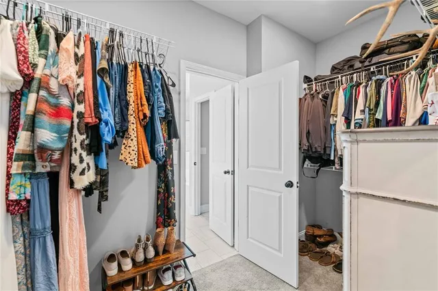 a view of walk in closet with clothes and shoes