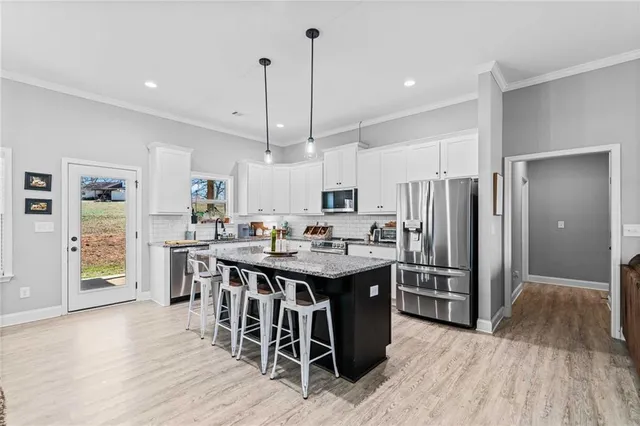 a kitchen with stainless steel appliances kitchen island granite countertop a table chairs refrigerator and sink
