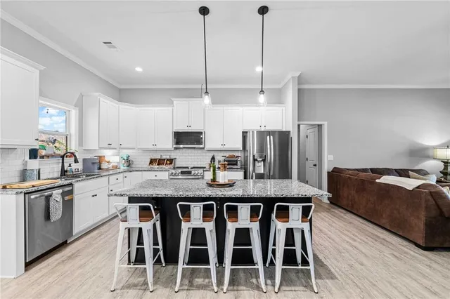 a kitchen with stainless steel appliances granite countertop a kitchen island hardwood floor sink and stove