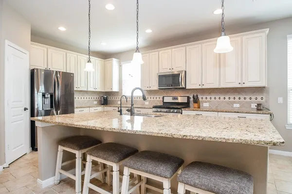 a kitchen with stainless steel appliances granite countertop a sink a stove a refrigerator a center island and cabinets