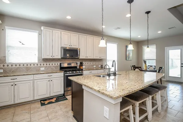 a kitchen with kitchen island granite countertop stainless steel appliances a sink a stove cabinets and a kitchen island