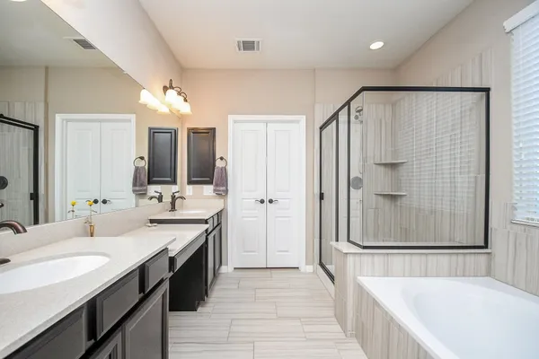 a spacious bathroom with a double vanity sink a mirror and shower