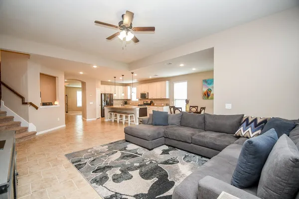 a living room with furniture kitchen view and a chandelier