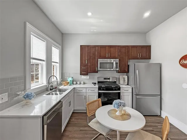 a kitchen with a refrigerator a sink a stove a microwave a dining table and chairs