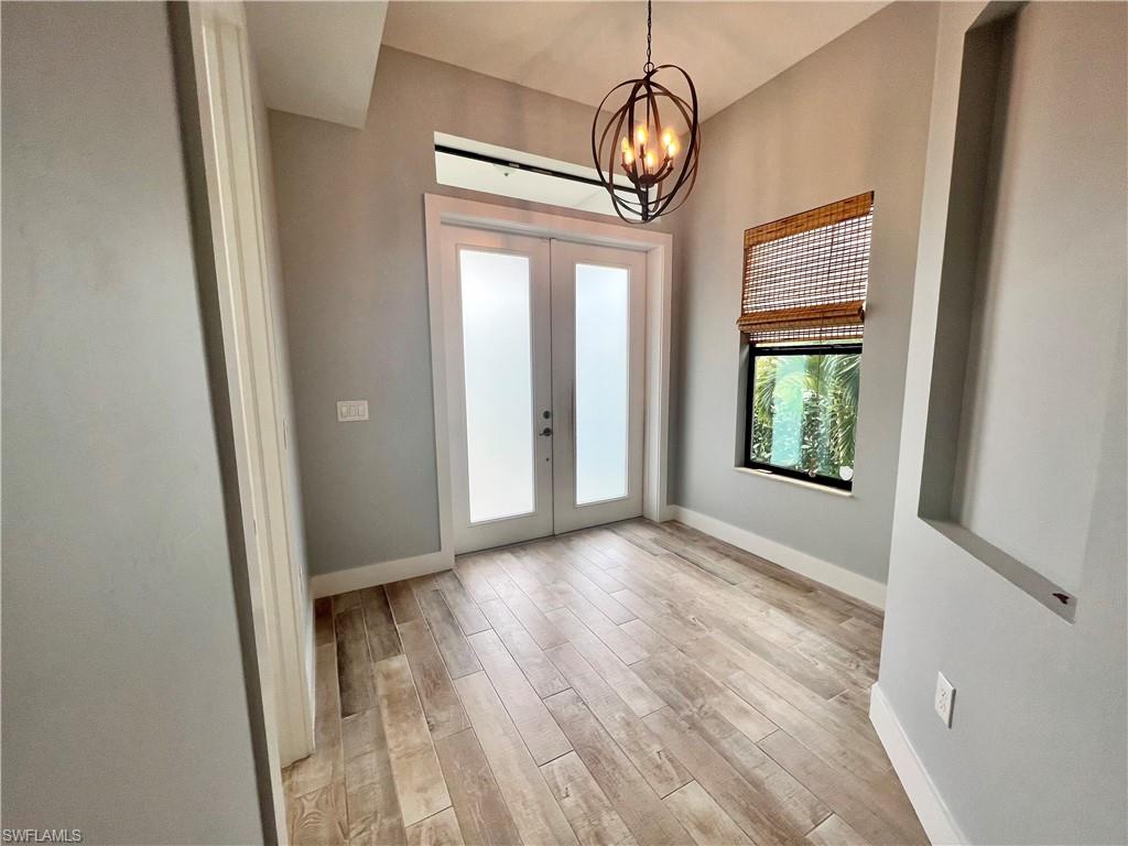 3128 Woodside Avenue Naples, FL 34112 - Photo 3 of 16 an empty room with wooden floor and windows