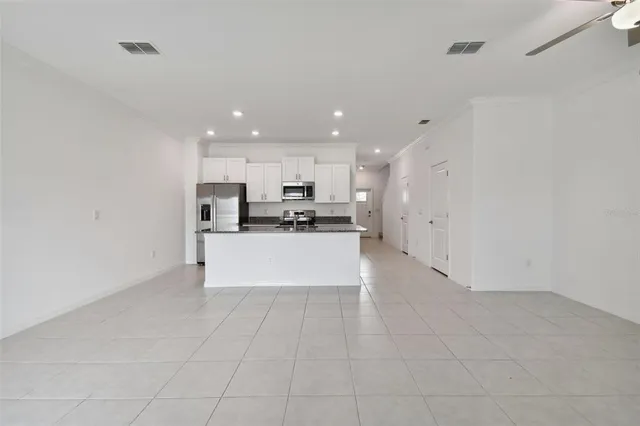 an empty room with a chandelier fan and closet area