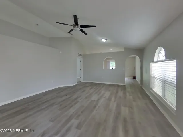 a view of empty room with wooden floor and fan