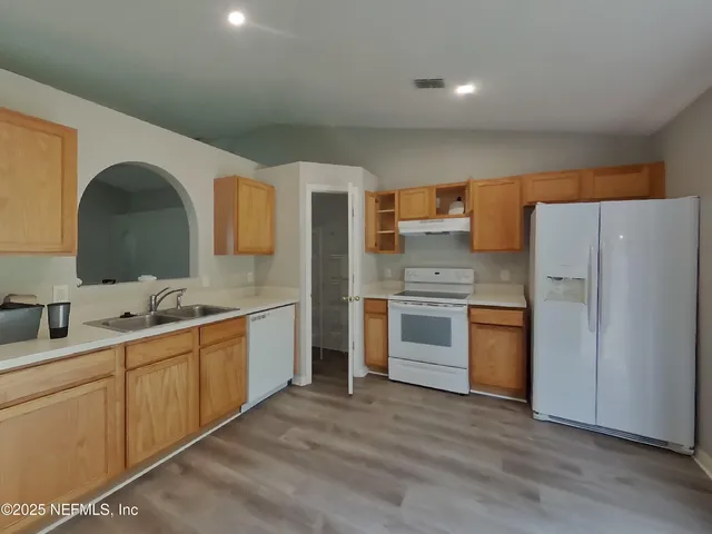 a kitchen with stainless steel appliances a sink cabinets and wooden floor