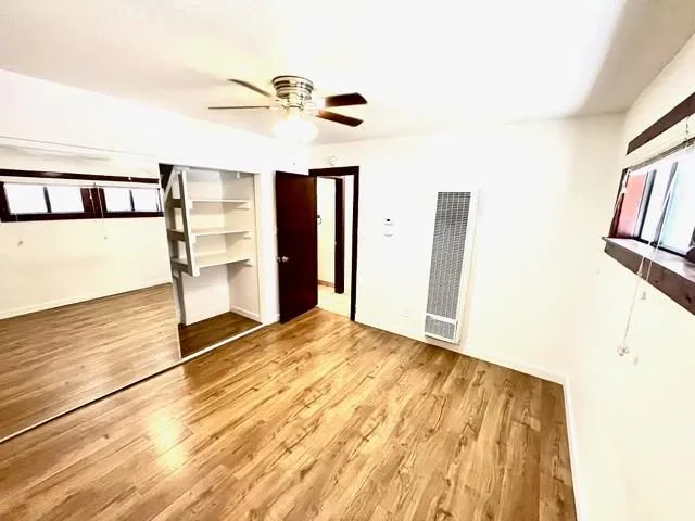 a view of a refrigerator in kitchen and an empty room with wooden floor