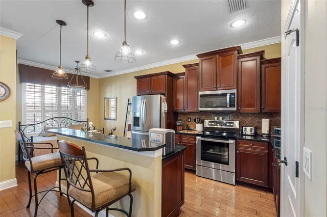 a kitchen with stainless steel appliances kitchen island granite countertop a stove top oven a sink a dining table and chairs