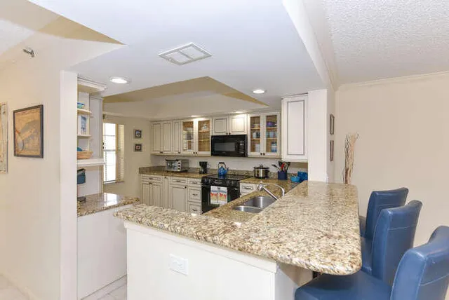 a kitchen with granite countertop a sink stove and cabinets