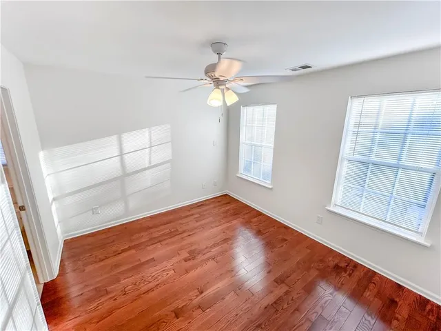 a view of empty room with wooden floor and fan