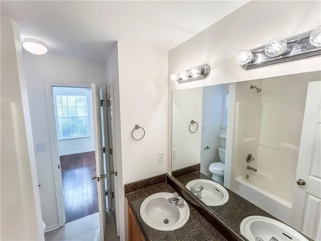 a bathroom with a granite countertop sink toilet a shower and a mirror