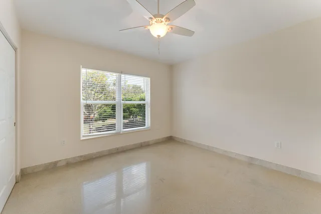 an empty room with a window and a fan