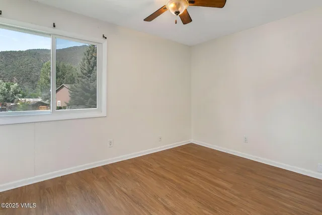 an empty room with a window and a ceiling fan