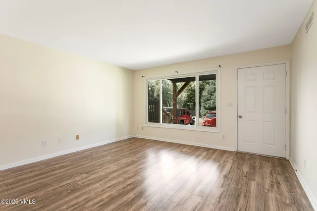an empty room with wooden floor and windows