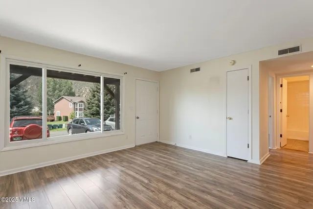 a view of an empty room with wooden floor and a window