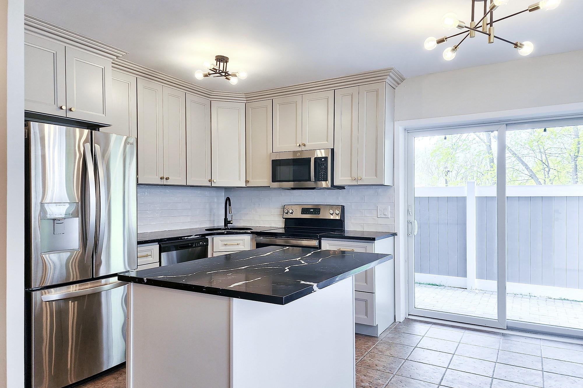 a kitchen with granite countertop a refrigerator stove and microwave