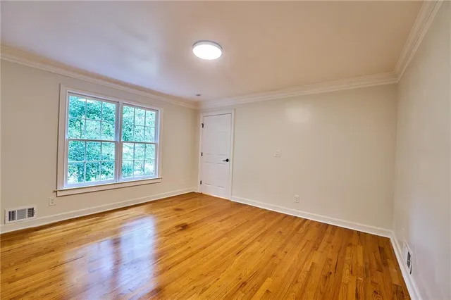 a view of an empty room with window and chandelier fan