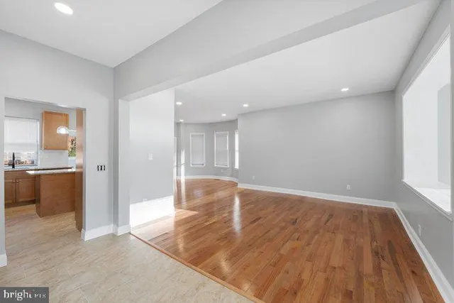 a view of empty room with wooden floor and a window