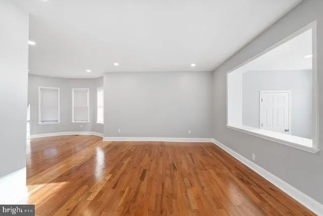 a view of an empty room with wooden floor and window