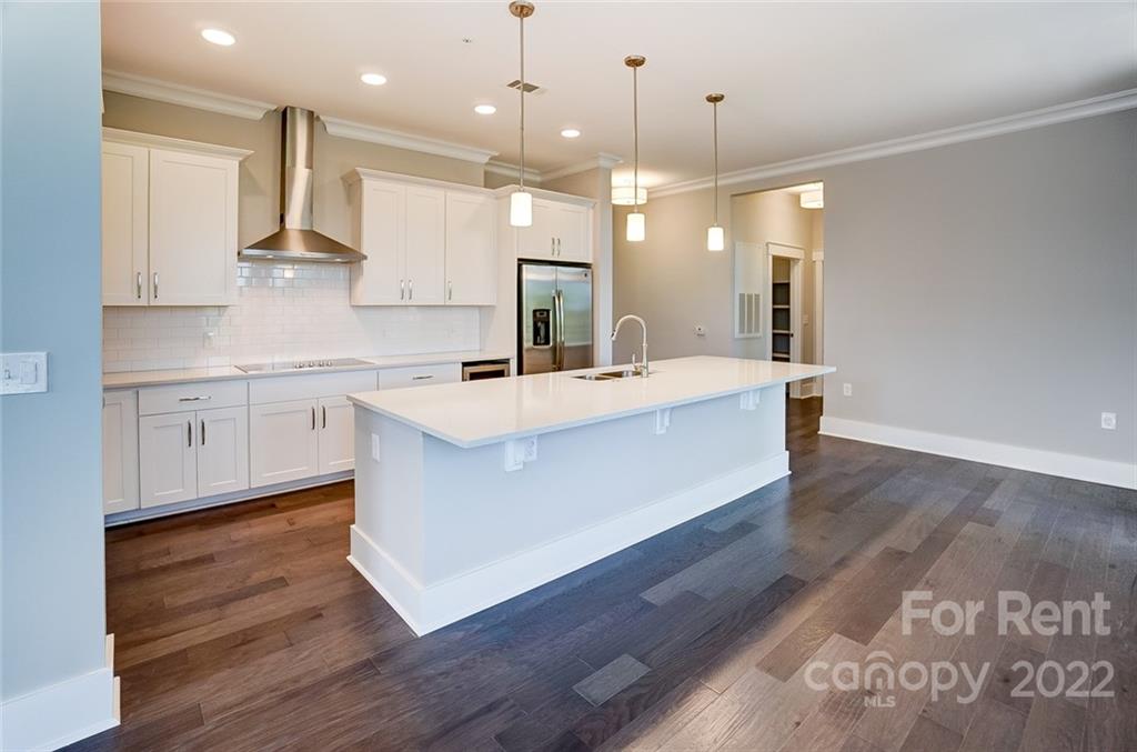 830 Providence Road, Unit 102 Charlotte, NC 28207 - Photo 6 of 31 a large kitchen with stainless steel appliances a large counter top a sink a refrigerator and a window