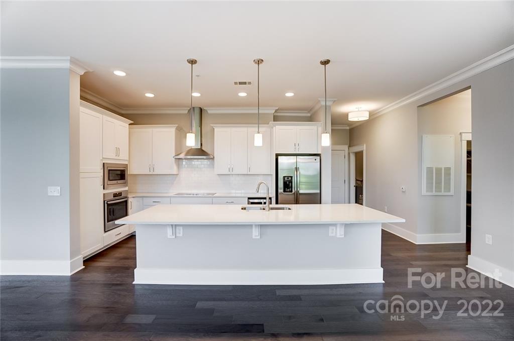830 Providence Road, Unit 102 Charlotte, NC 28207 - Photo 7 of 31 a large white kitchen with a large island oven a stove and a refrigerator
