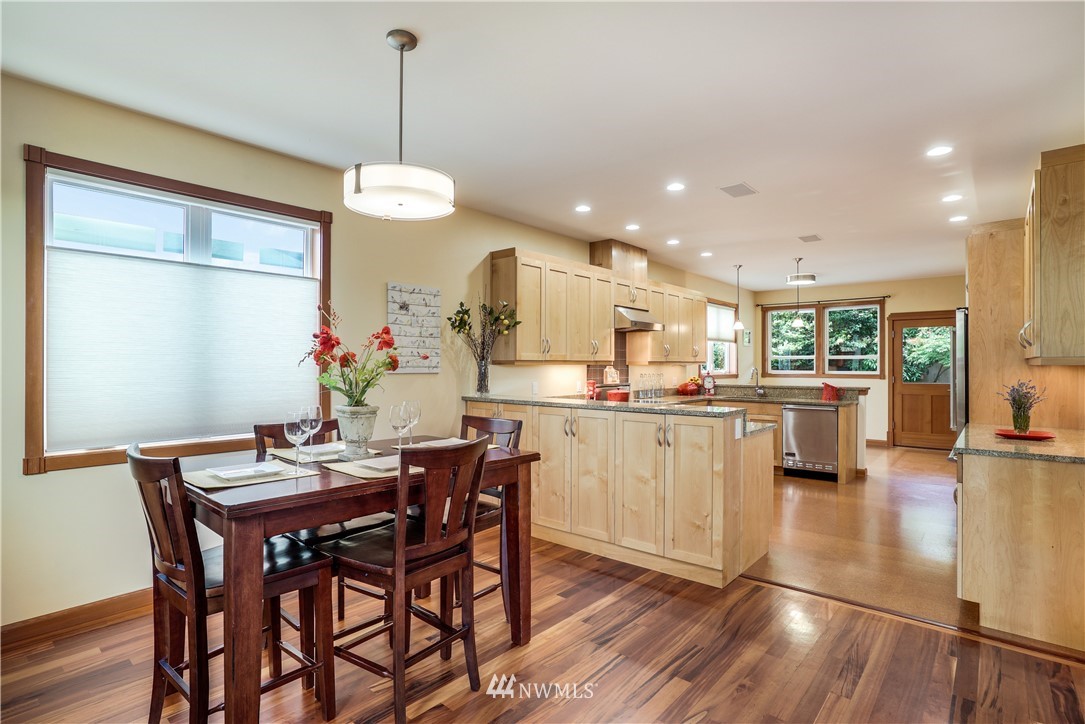 1023 West Ruffner Street Seattle, WA 98119 - Photo 5 of 25 a kitchen with stainless steel appliances kitchen island granite countertop a dining table chairs and white cabinets