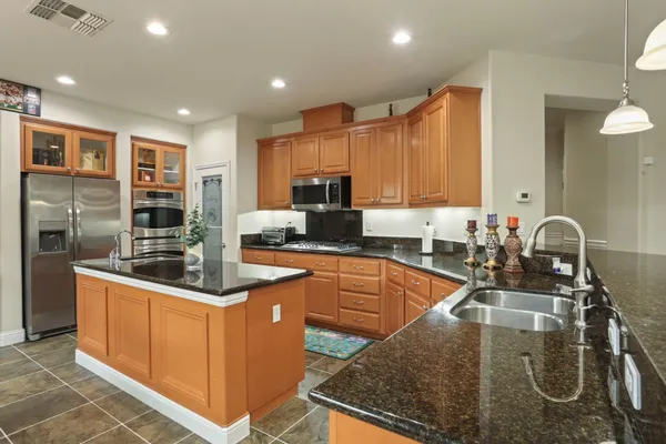 a kitchen with stainless steel appliances granite countertop a sink a stove and a refrigerator