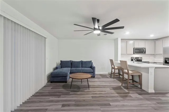 a living room with stainless steel appliances kitchen island granite countertop furniture and a rug
