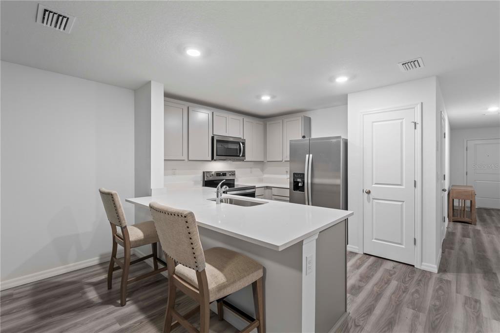 959 Spotted Egret Loop Ruskin, FL 33570 - Photo 19 of 36 a kitchen with a dining table chairs refrigerator and cabinets