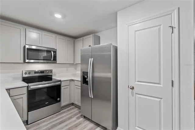 a metallic refrigerator freezer and a stove top oven in a kitchen