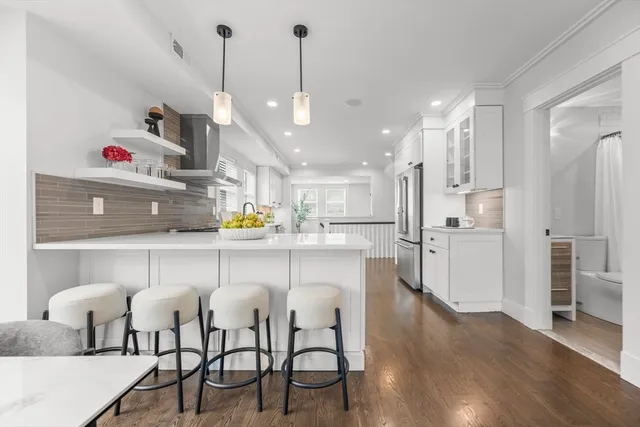 a kitchen with stainless steel appliances kitchen island granite countertop a table chairs in it and wooden floors