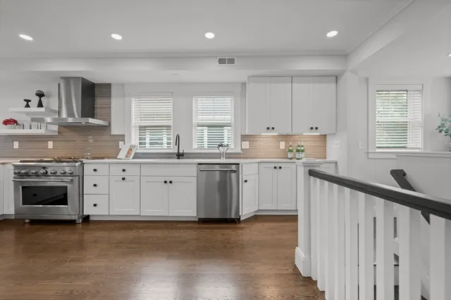 a kitchen with stainless steel appliances granite countertop a stove a sink and white cabinets
