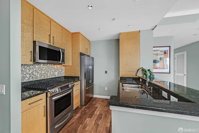 a kitchen with stainless steel appliances granite countertop a stove a sink and a microwave