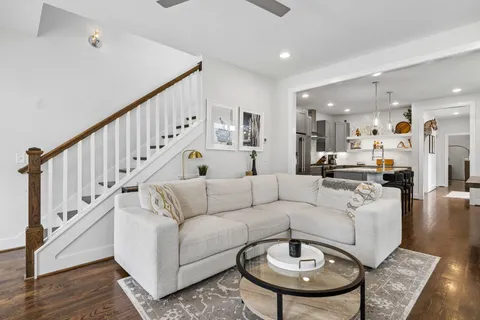 a living room with furniture kitchen view and a wooden floor