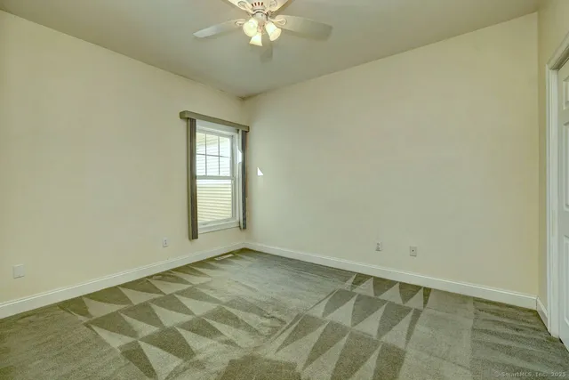 an empty room with a chandelier fan and windows