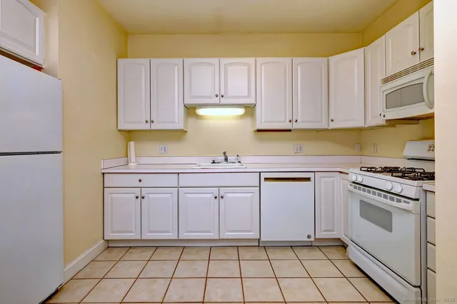 a kitchen with white cabinets appliances and a sink