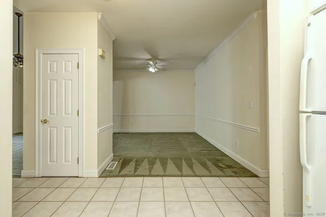 a view of a livingroom with an empty space a ceiling fan and window