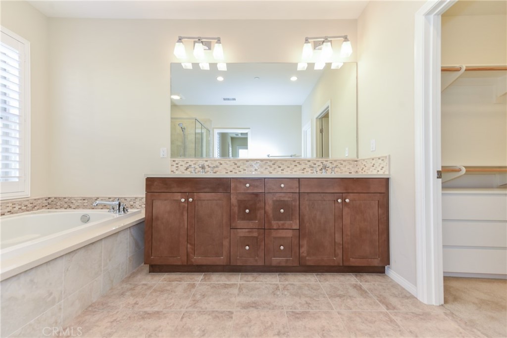 67 Elmdale Irvine, CA 92620 - Photo 23 of 39 a bathroom with a granite countertop sink a large mirror and bathtub