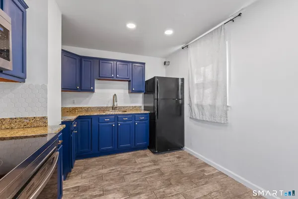 a kitchen with stainless steel appliances granite countertop a refrigerator a stove and a sink with wooden cabinets