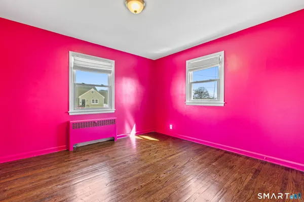 a view of empty room with wooden floor and window