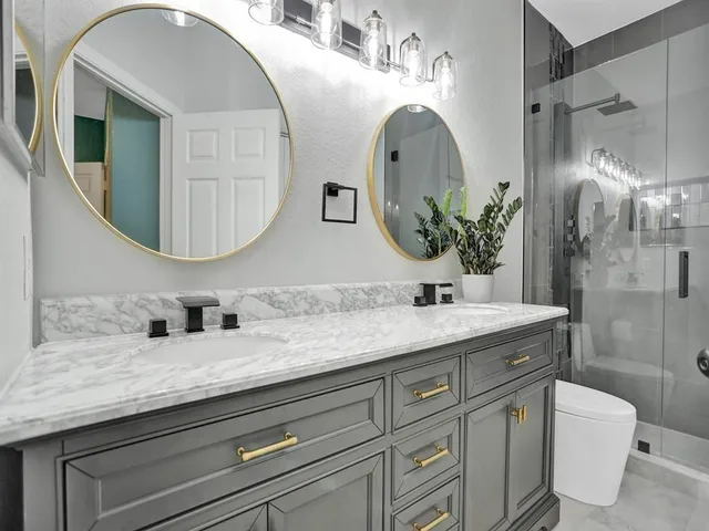 a bathroom with a granite countertop toilet sink and mirror