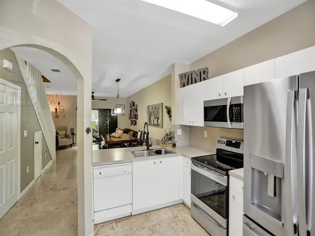 a kitchen with a sink stainless steel appliances a refrigerator and cabinets