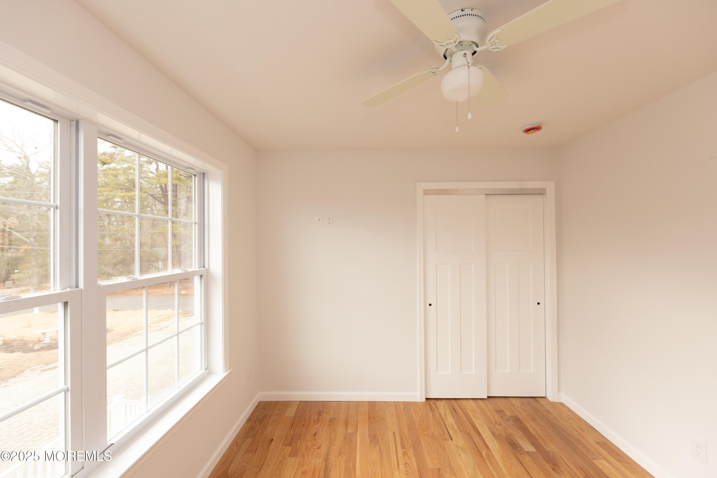 1517 Whitcomb Road Forked River, NJ 08731 - Photo 12 of 18 an empty room with wooden floor fan and windows