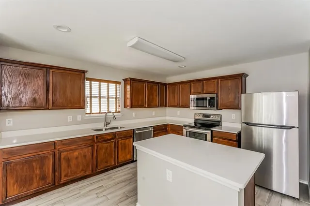 a view of a kitchen with a sink dishwasher a refrigerator and wooden cabinets