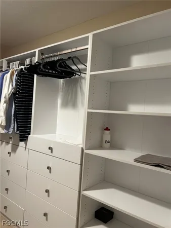 a view of walk in closet with clothes and shoes